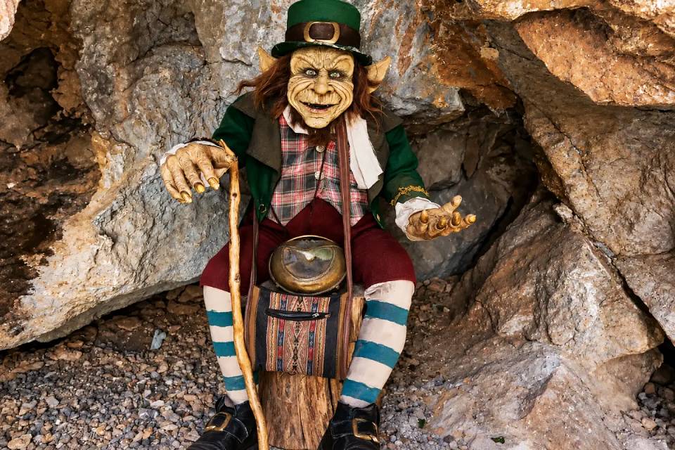 Duende Maldito con sombrero verde y sonrisa traviesa entre las rocas