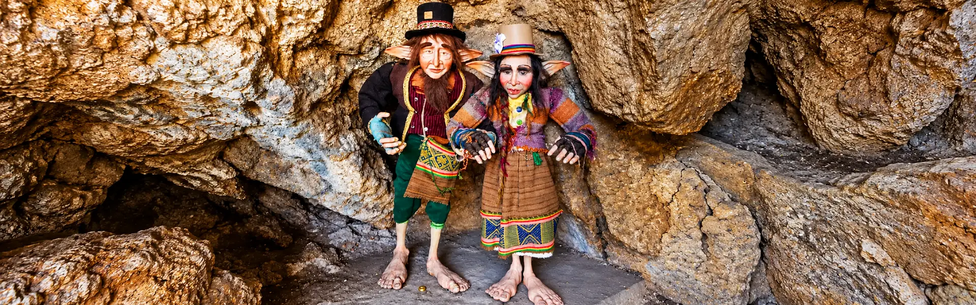 Dos figuras de duendes con sombreros y ropa colorida dentro de una gruta