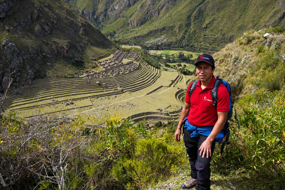 Guía de montaña en un mirador con vista a los andenes y construcciones incas de Patallacta