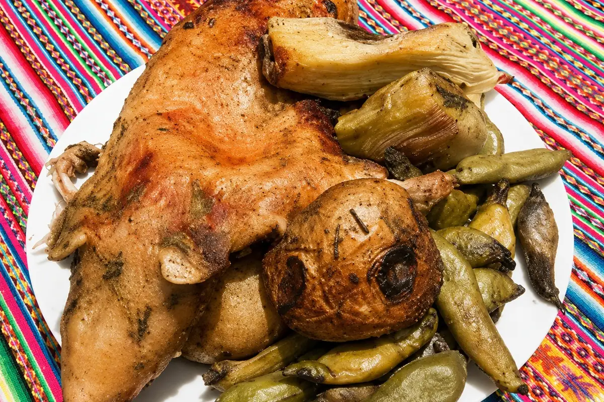 Pachamanca con cuy servida con papa, habas y vegetales andinos sobre una manta tradicional