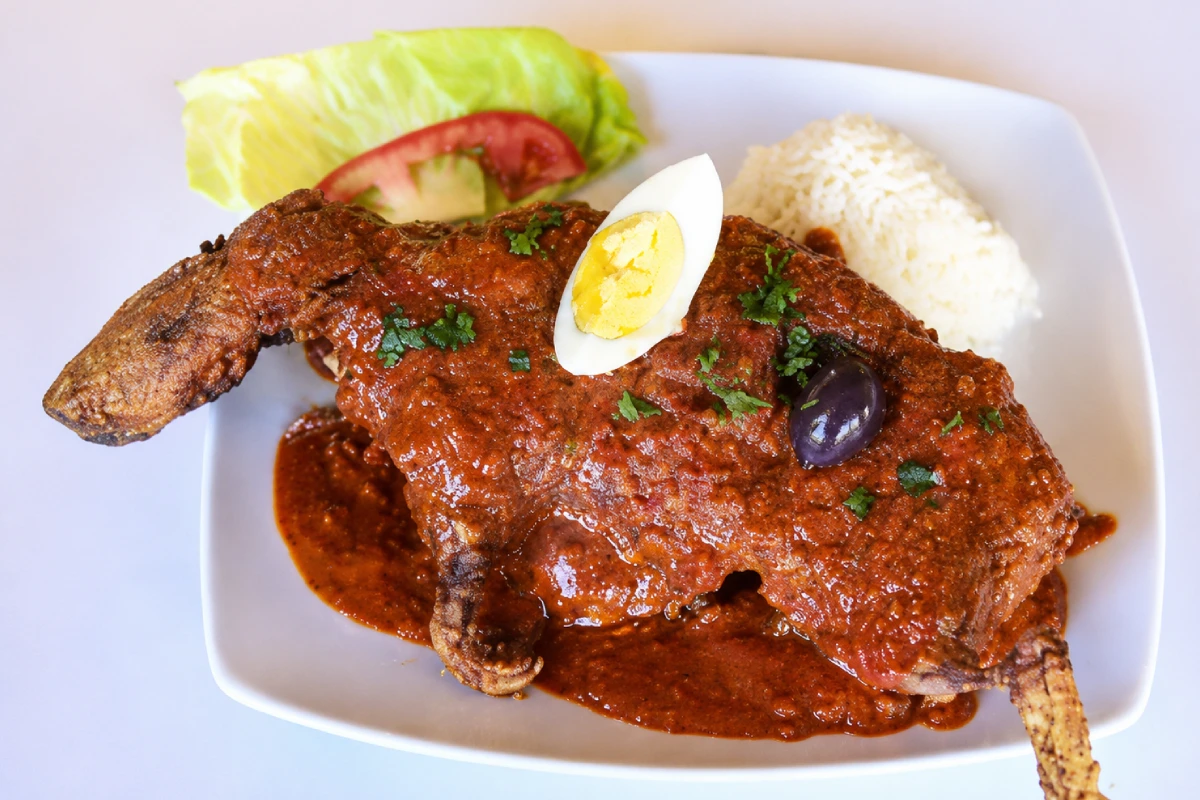 Picante de cuy servido con salsa de ají, arroz, huevo, aceituna y ensalada