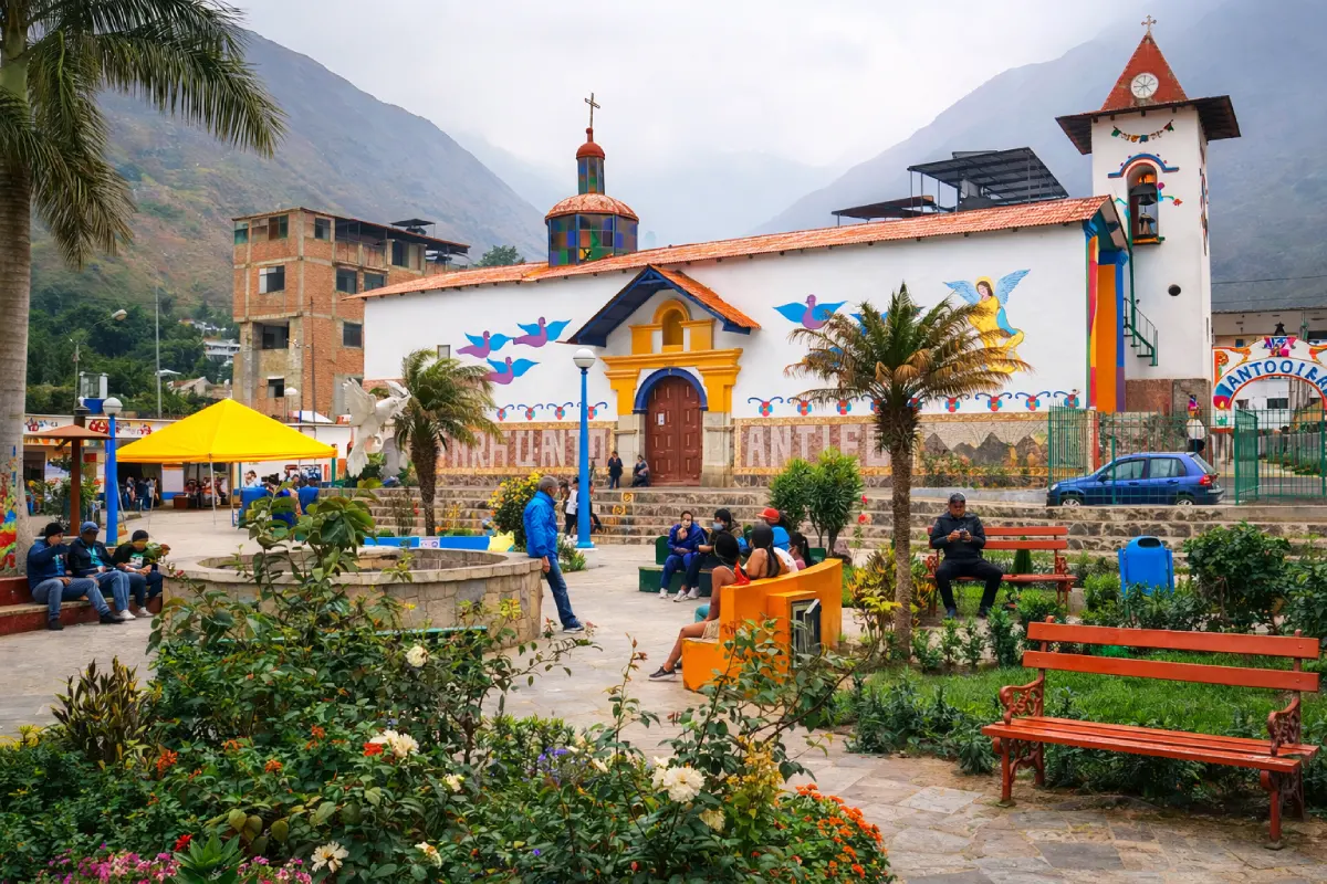 Plaza principal de Antioquía con su iglesia decorada con murales coloridos, jardines, bancas y visitantes en un pueblo de Huarochirí, Lima