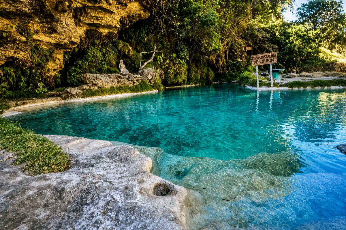 Poza termal de agua turquesa en Churín, rodeada de rocas, vegetación y entorno natural en la sierra de Lima.