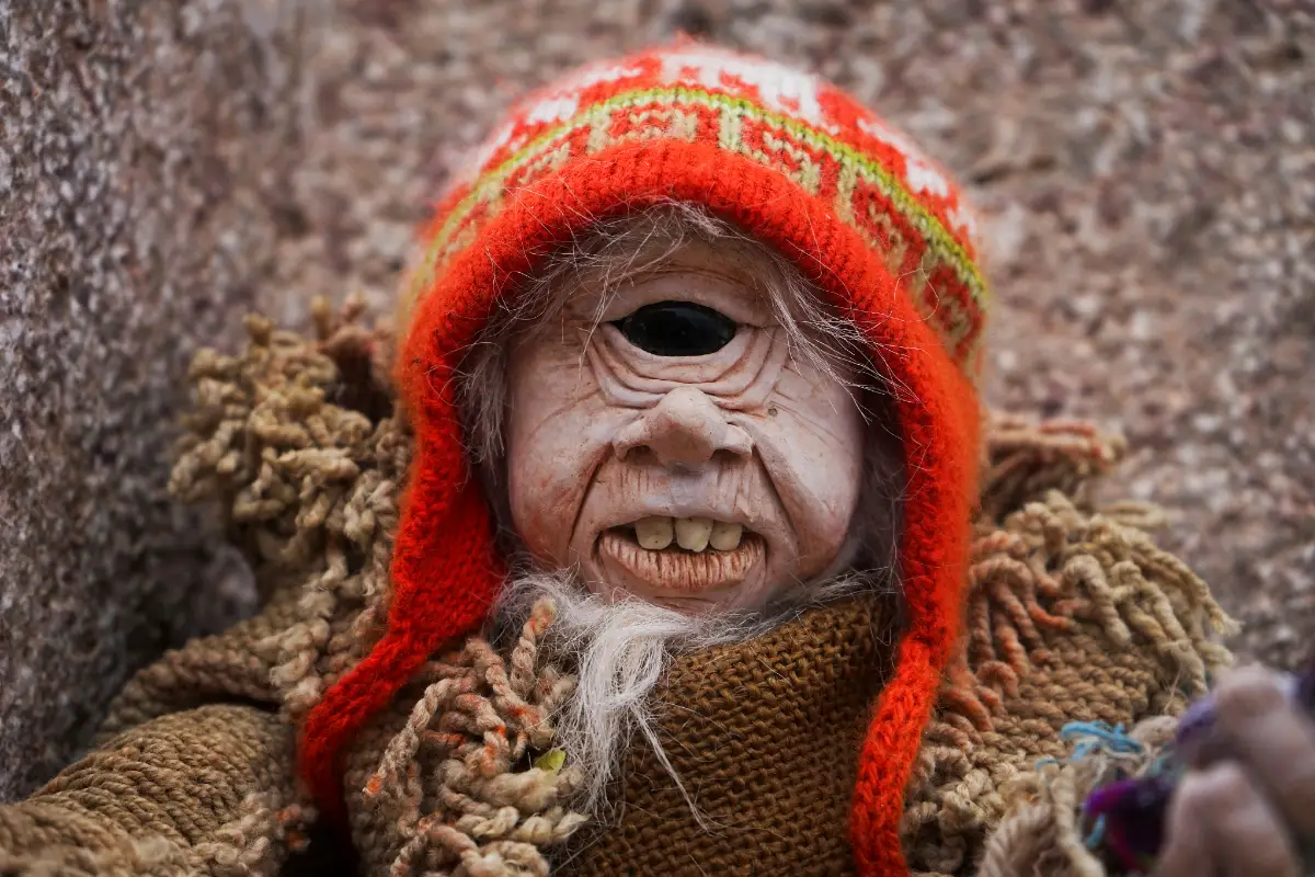 Figura de un duende de un solo ojo con gorro rojo y ropa tejida