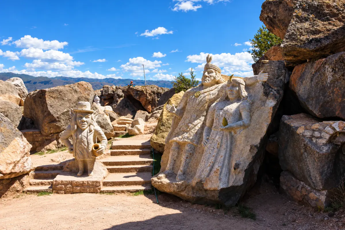 Esculturas de una pareja con vestimenta andina y un duende de piedra en Cusco