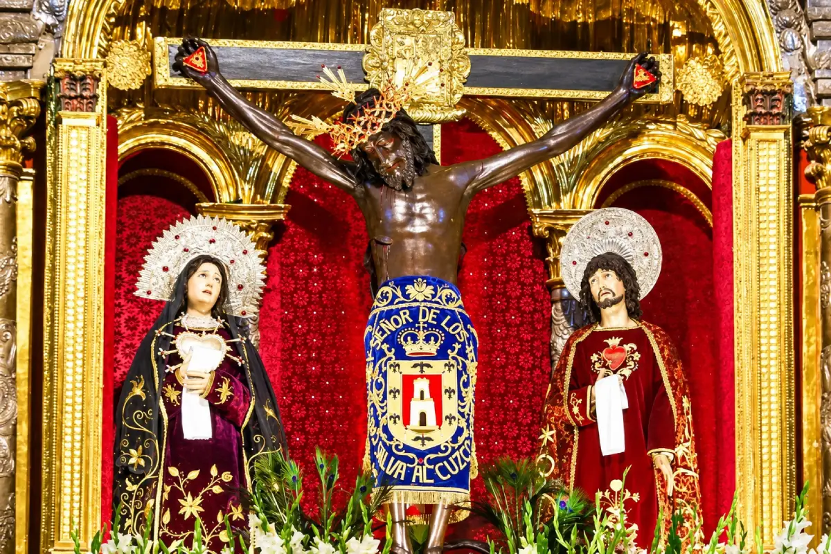 Señor de los Temblores o Taytacha crucificado, acompañado por la Virgen Dolorosa y San Juan Evangelista ante un retablo dorado