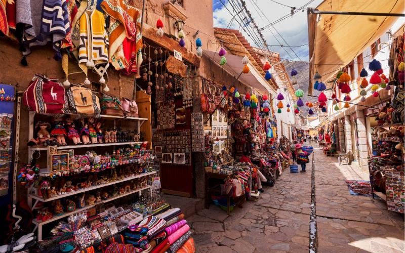 Mercado artesanal de Pisac entre calles de piedra y coloridos textiles andinos | Trekero